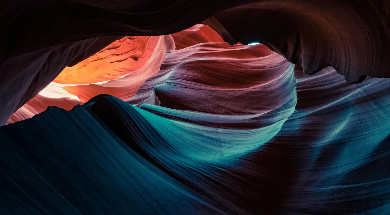 Vivid blue, teal, red and orange sandstone swirls inside Antelope Canyon — the kind of handheld shot photographers come to Page, Arizona to capture